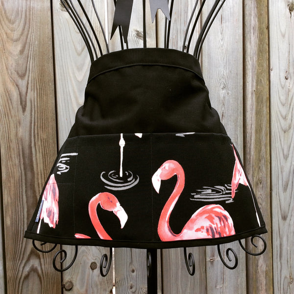 black waist apron with pink flamingoes on pocket panel and black ties