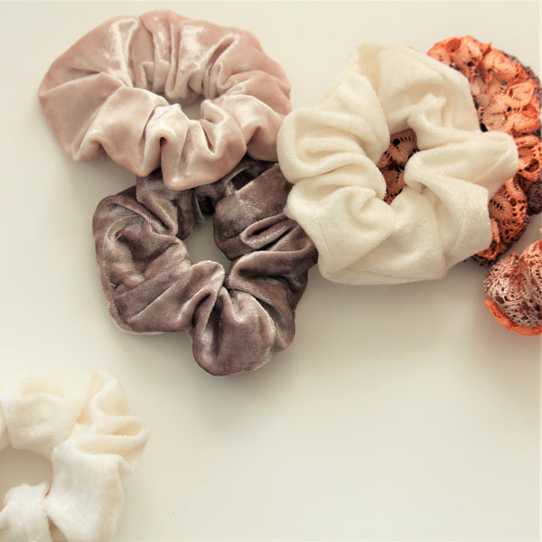 Velvet and lace hair scrunchies scattered on a white surface