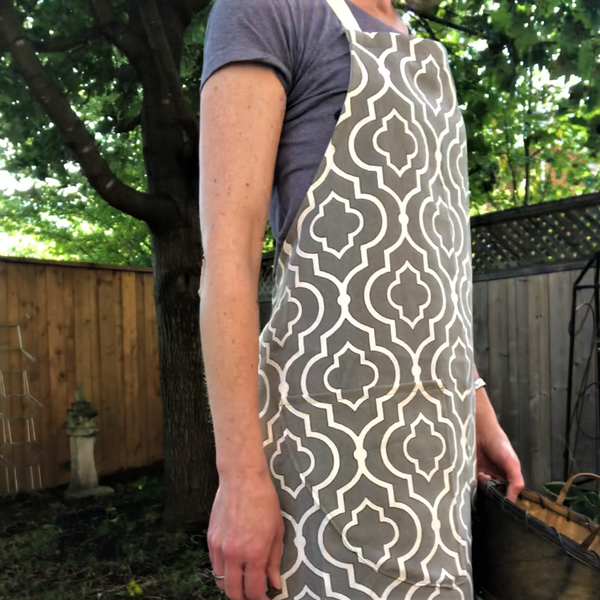 a woman in the garden wearing a full apron in taupe and ivory geometric pattern