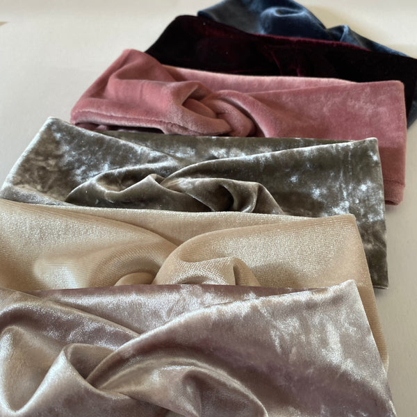 A row of handmade velvet headbands are lined up against a white background.