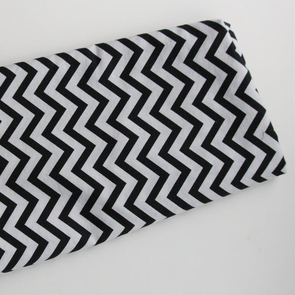 A folded piece of black and white chevron pattern fabric lies on a white background.