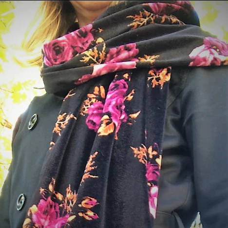 handmade velvet scarf with black and magenta floral pattern worn by a woman beside a tree
